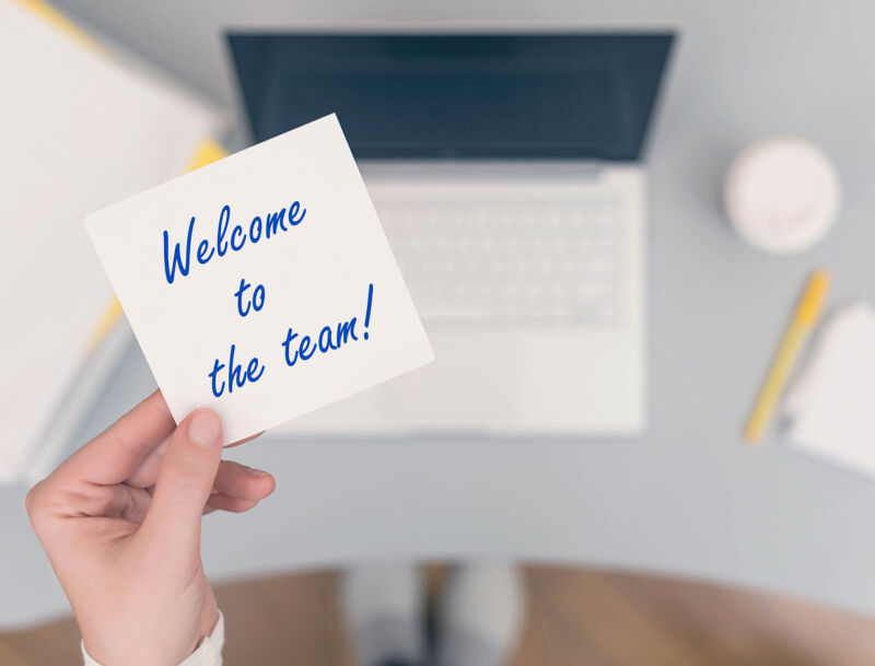 Woman,clerk,sitting,holding,note,paper,sticker,with,welcome,to