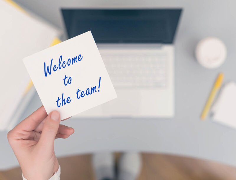 Woman,clerk,sitting,holding,note,paper,sticker,with,welcome,to